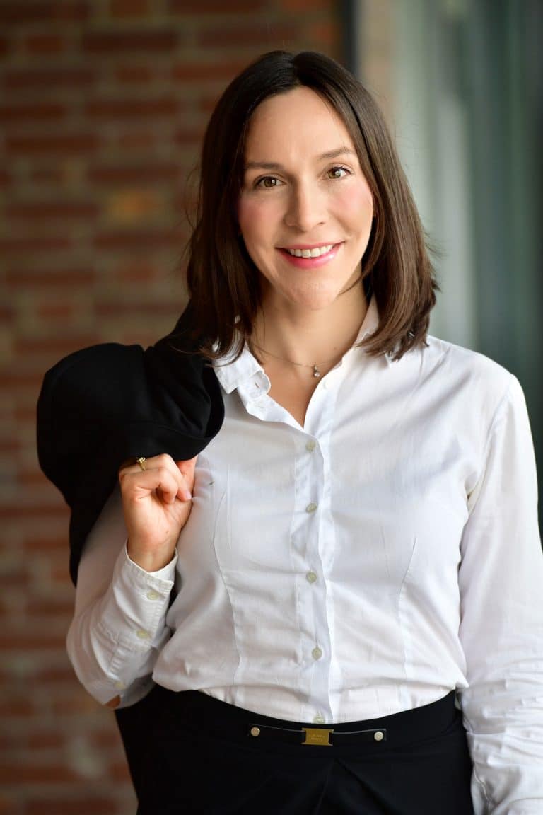 Junge Rechtsanwältin mit weißem Hemd und schwarzem Blazer über der Schulter